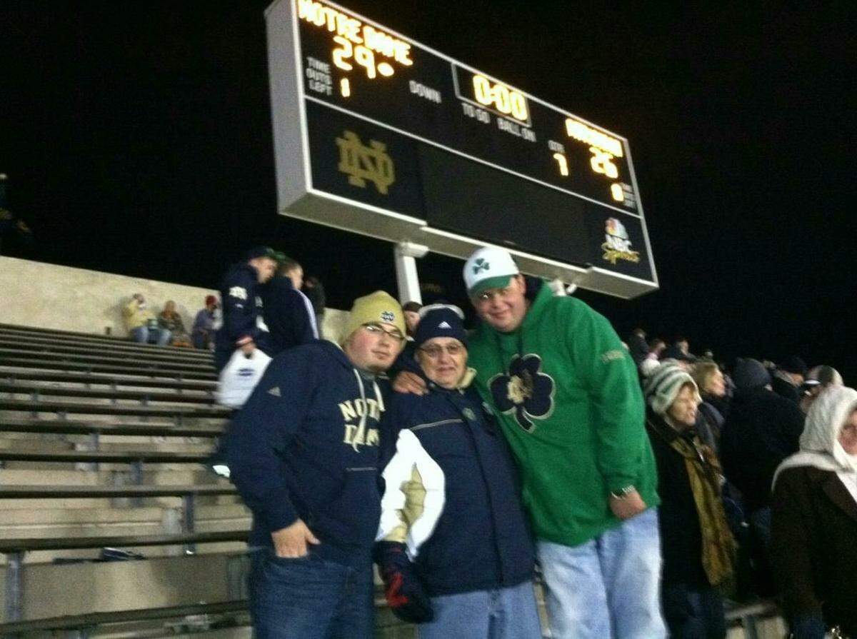 Anthony and Travis McCullough pose with their grandfather on Nov. 3, 2012, beneath the Notre Dame Stadium scoreboard after the Irish won 29-26 in triple OT. To this day, Anthony and Travis swear their grandfather predicted an OT Irish win during breakfast at Bob Evans, which is why they wanted to pose with the scoreboard afterward.