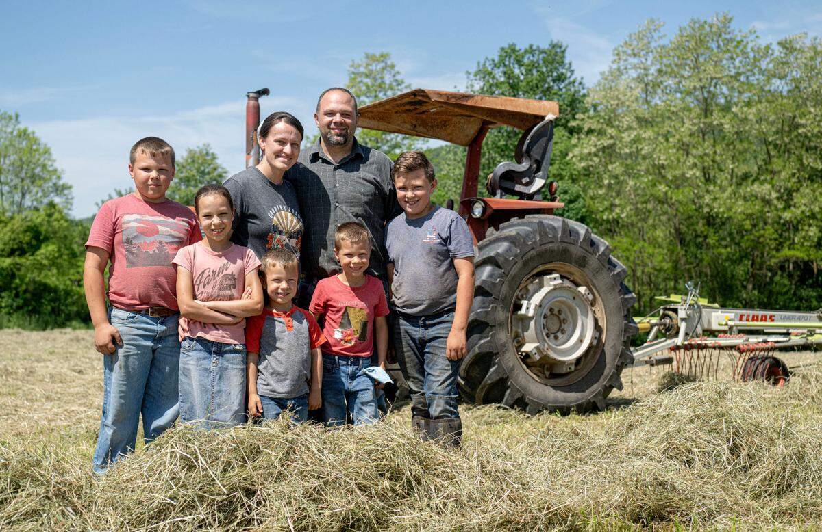 Valerie and Darren King with their kids Jadon, 10, Katriel, 8, Landon, 4, Andre, 6 and Kenton, 12 in a hay field at Stem to Stable Farm on Tuesday, May 21, 2024.