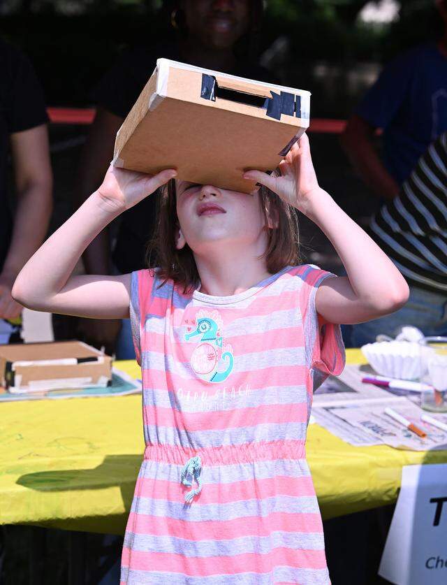 Vivienne Ashby, 7, from Falls Church, Virginia, looks at the color spectrum of the sun through a diffraction grating viewer during Wednesday’s Children and Youth Day at the 57th Central Pennsylvania Festival of the Arts in State College.