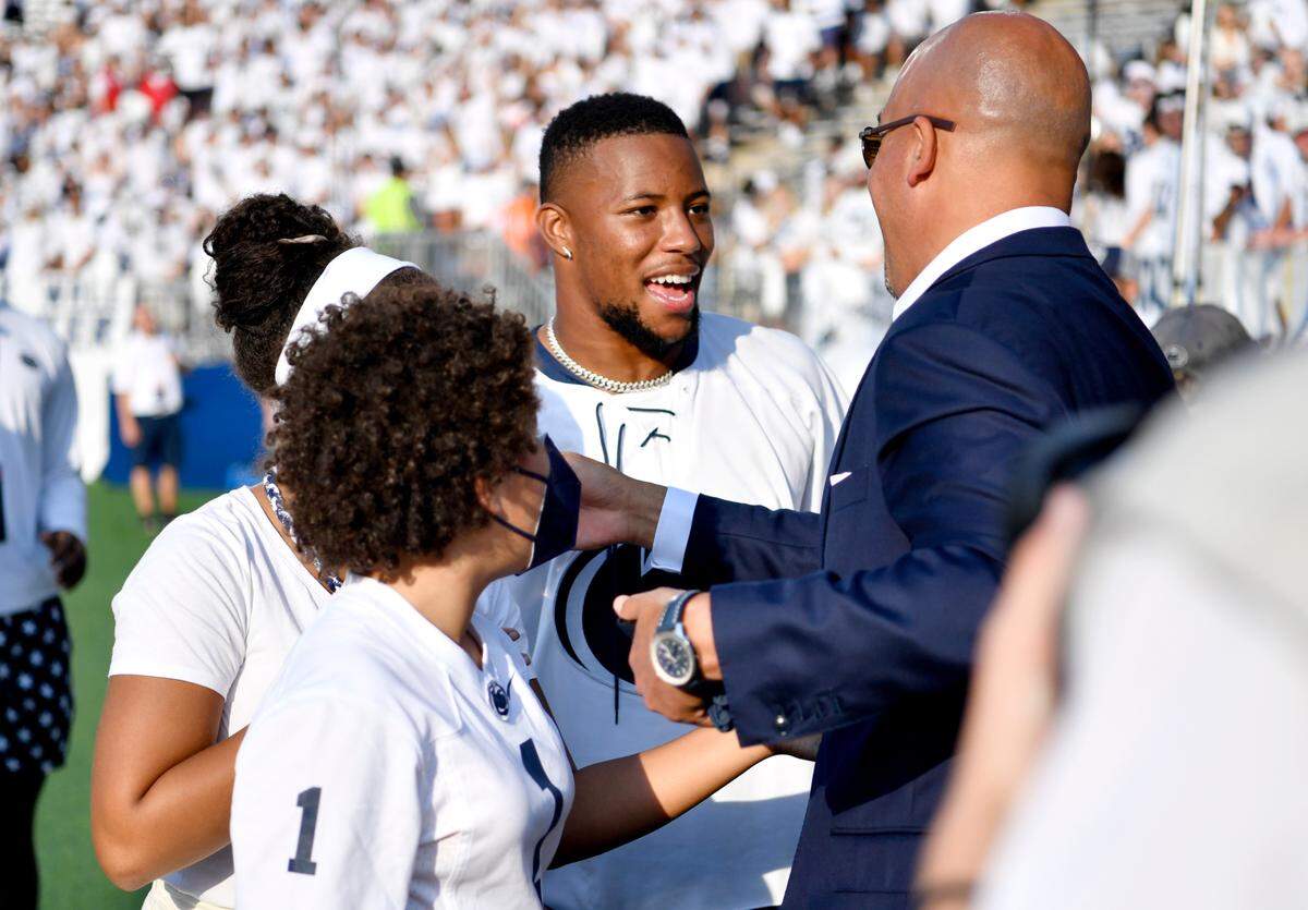 Former Penn State stand out and current New York Giants running back Saquon Barkley greets coach James Franklin and his daughters at Beaver Stadium before the game against Auburn.