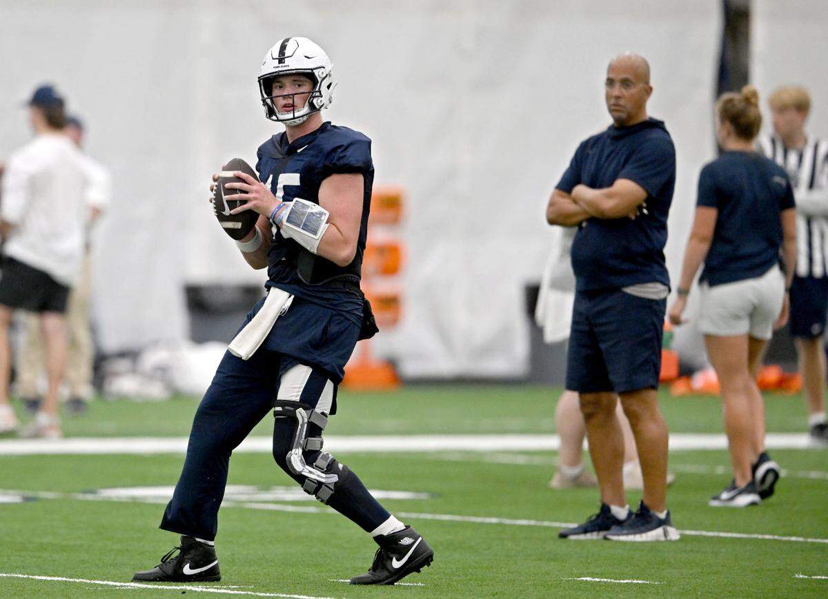 Penn State quarterback Drew Allar drops back to make a pass as coach James Franklin watches during practice on Saturday, Aug. 3, 2024.