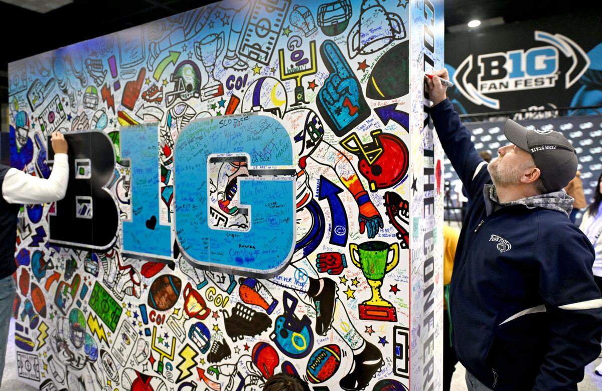 Nittany Lions fans Doug Boyles writes “PSU #1” on a color wall at the Big Ten Fan Fest sponsored by Dr Pepper at the Indianapolis Convention Center before the game on Saturday, Dec. 7, 2024.