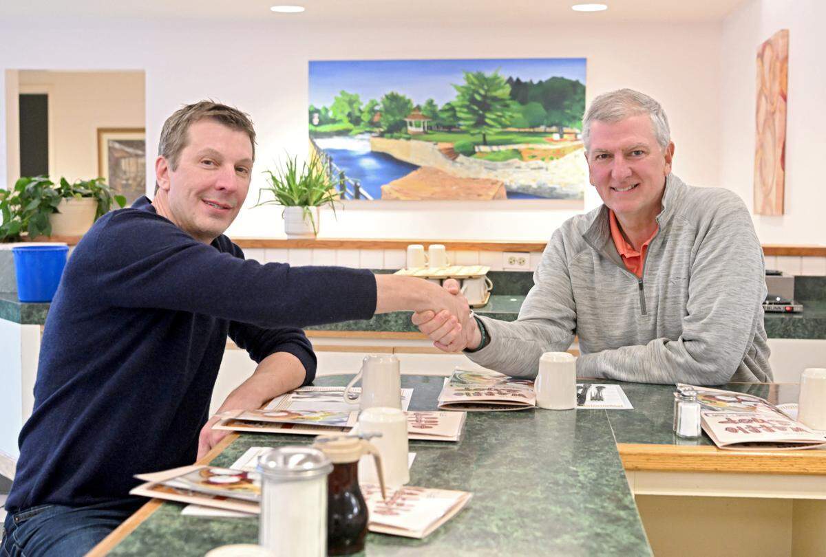 New owner of The Waffle Shop Duane Reese shakes hands with former owner Greg Kight at the Bellefonte location on Friday, March 10, 2023. They recreated a photo of when Kight bought the business from John Dimakopoulos.