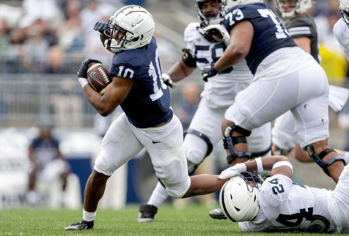 Running back Nick Singleton gets tripped up by linebacker Ta’Mere Robinson during the Penn State Blue-White game on Saturday, April 15, 2023.