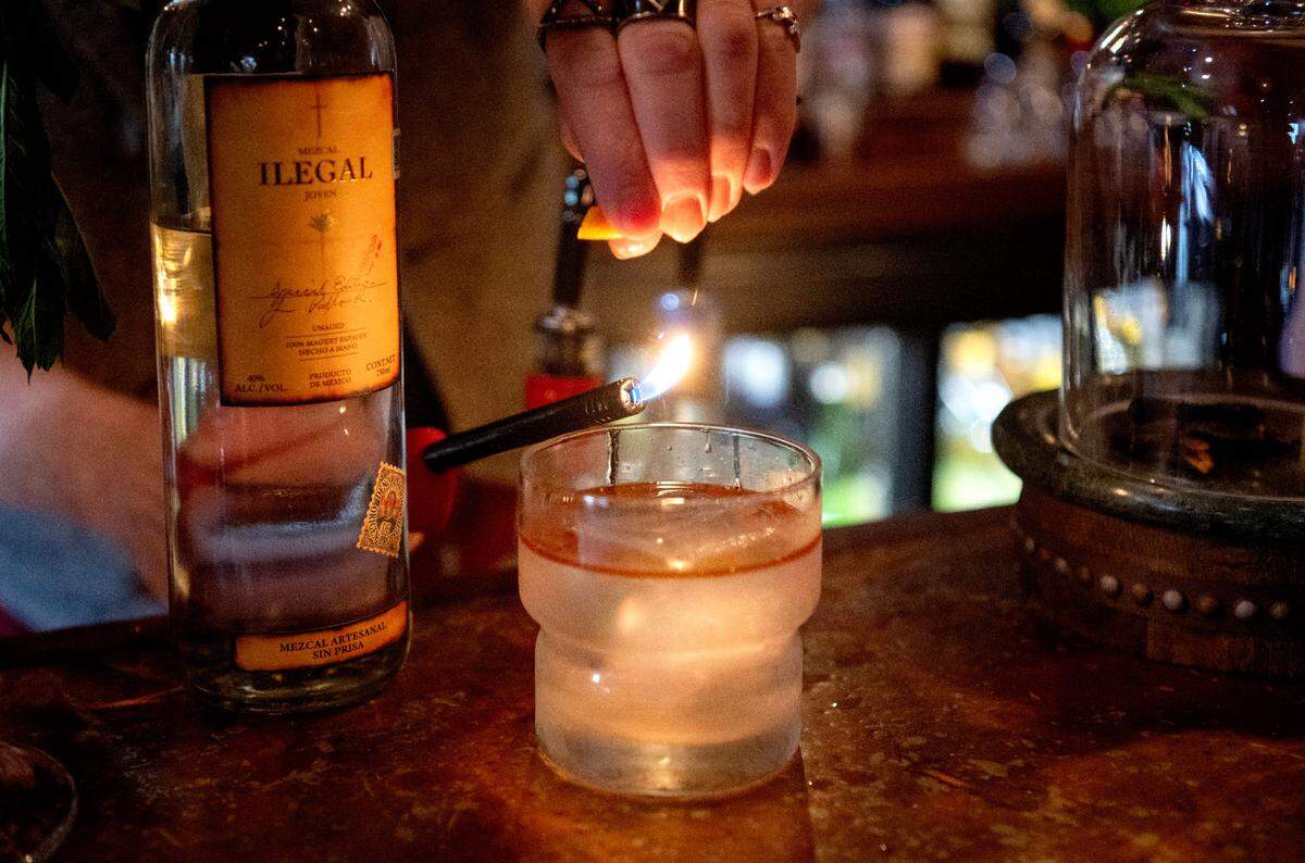 Sc’Eric Horner adds a flamed orange peel to a White Lodge cocktail at Pine Grove Hall on Thursday, May 23, 2024.