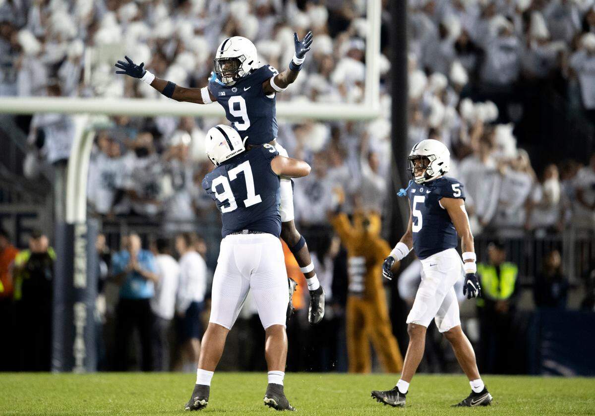 Penn State defensive tackle PJ Mustipher holds up cornerback Joey Porter Jr. after his interception during the game.