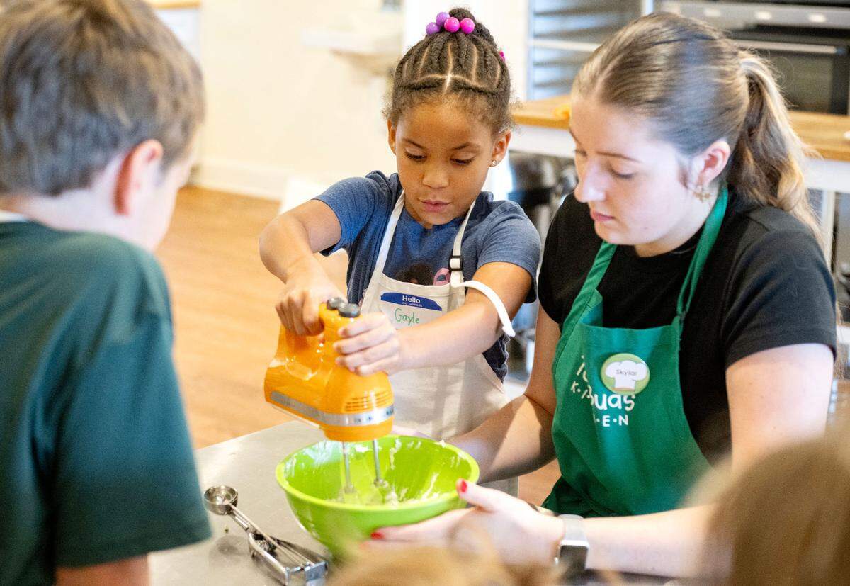 Counselor Skylar Shultz helps campers mix together the creme cheese filling for their apple oatmeal cream pies during Taste Buds Kitchen summer camp on Tuesday, July 1, 2025.