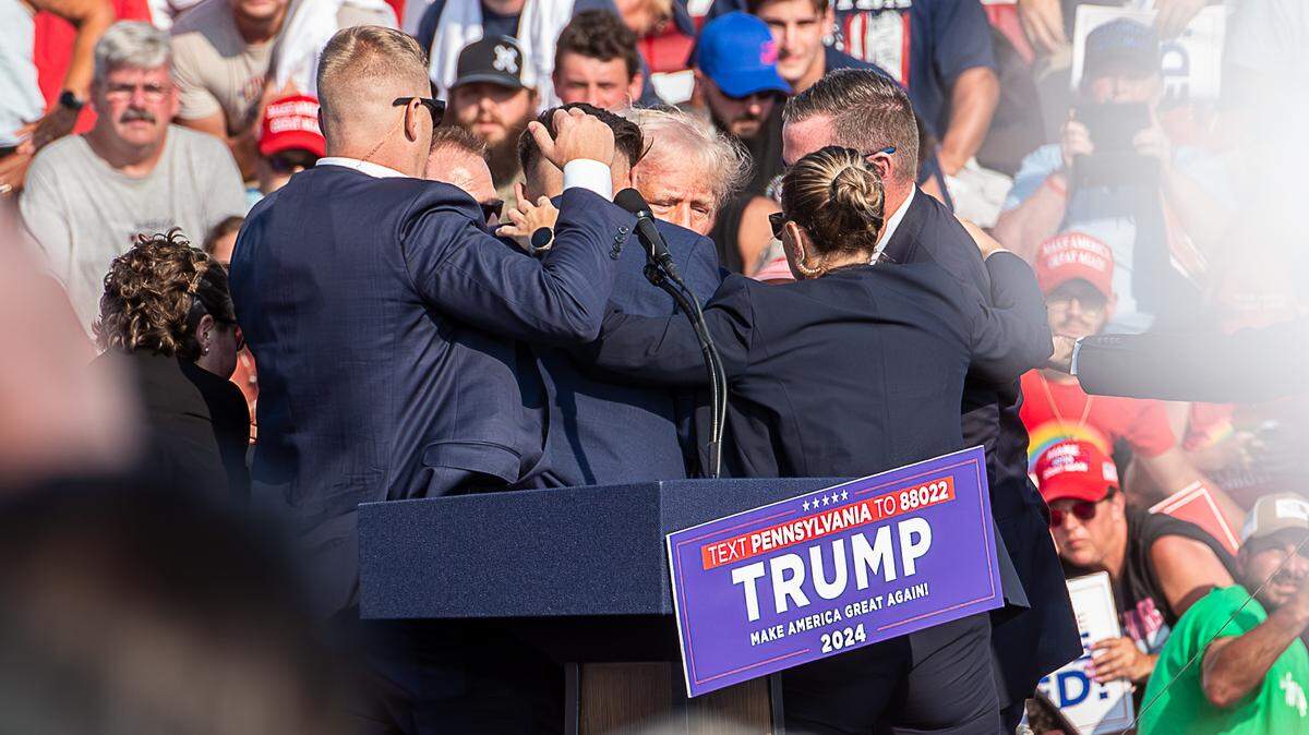 The Secret Service immediately surround former President Trump after he was shot during his campaign stop at the Butler Farm Show grounds on Saturday, July 13, 2024.