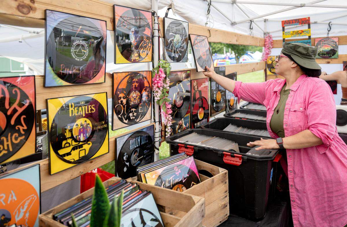 Koko from Astro Vinyl Art hangs up a variety of pieces during the People’s Choice Festival of Pennsylvania on Thursday, July 10, 2025.
