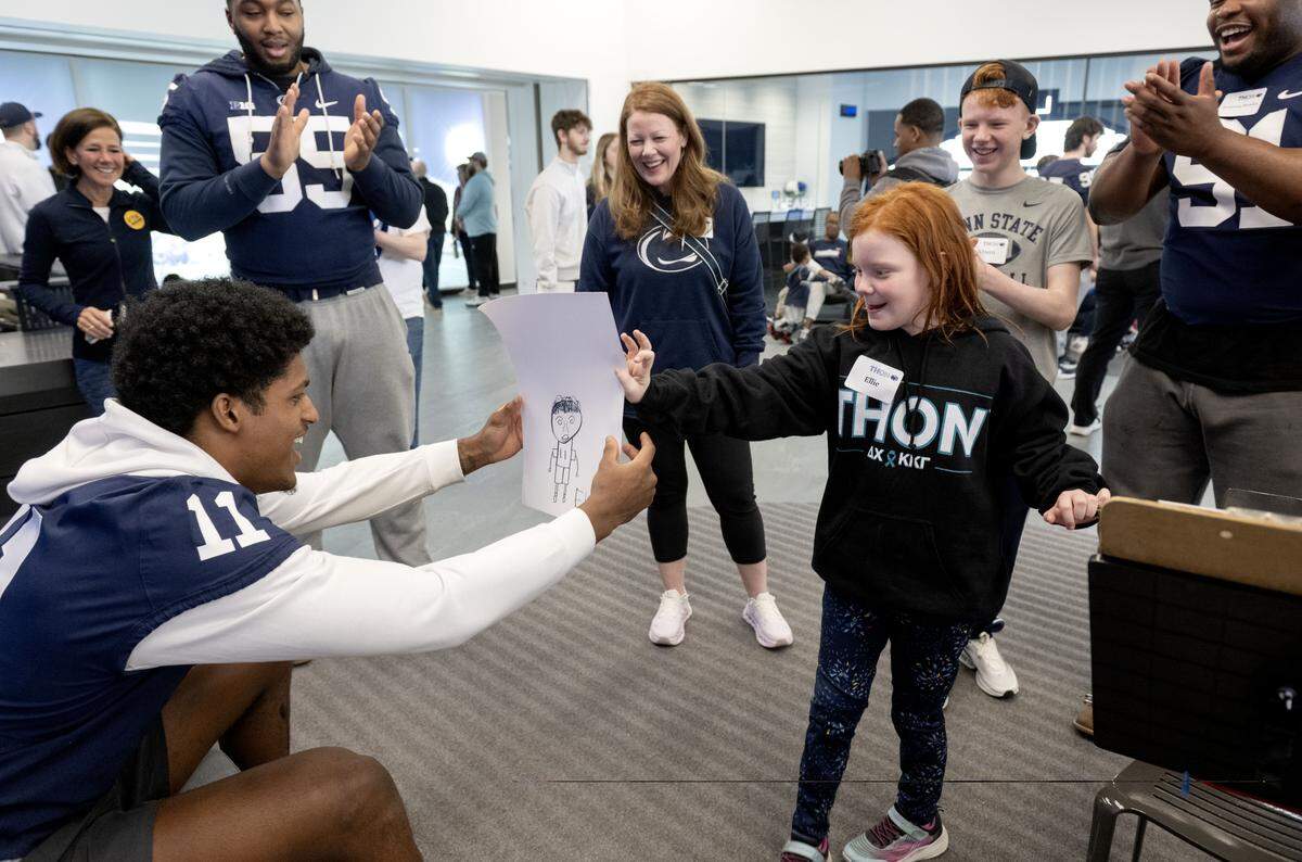 Ellie Bonn, 8, gives Penn State linebacker Lavar Arrington II a drawing of him during the Thon Explorers event at the Lasch Building on Saturday, Feb. 21, 2026.  