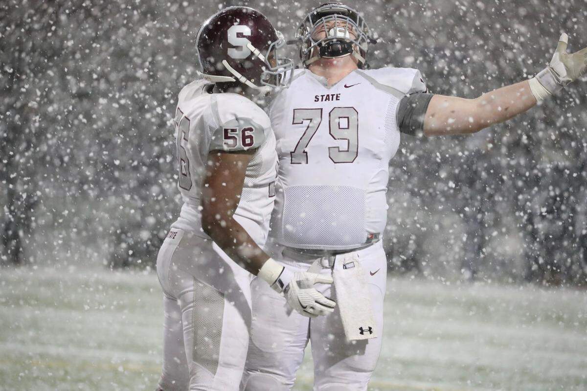 State College’s Jacob Hodge (56) and Addison Darcy (79) enjoy the snow during the Little Lions’ 42-21 win over McDowell High School in the PIAA Class 6A subregional football game at Erie Veterans Memorial Stadium on Friday in Erie.