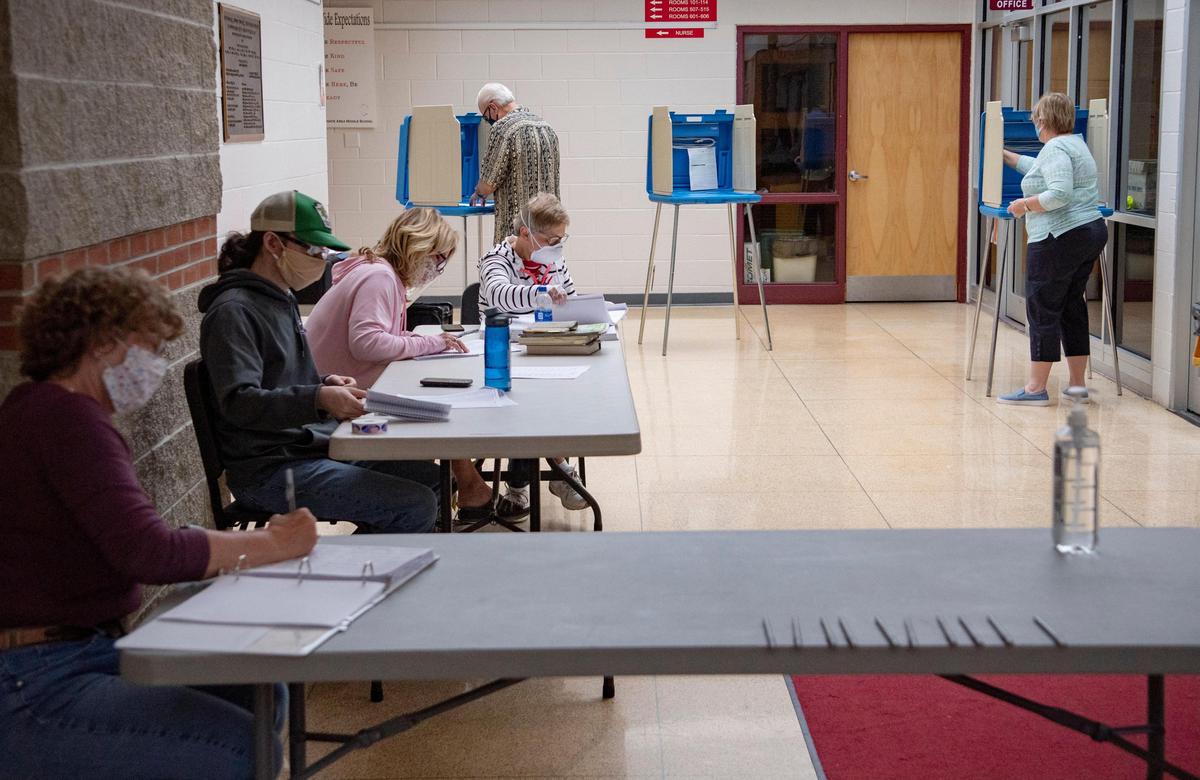 Poll workers wear masks and sanitize the voting booths Tuesday as a man votes at the Bellefonte Middle School precinct.