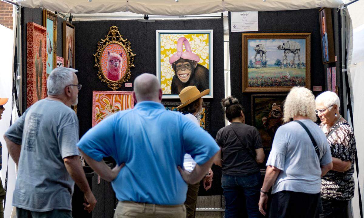 Visitors browse paintings by Tara Turnbull in her booth on Allen Street during the Central Pennsylvania Festival of the Arts on Friday, July 11, 2025.