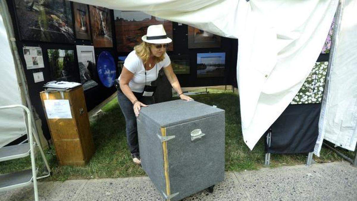 Patty Albin moves boxes of items before opening her and her husband’s booth at the Central Pennsylvania Festival of the Arts on Friday.
