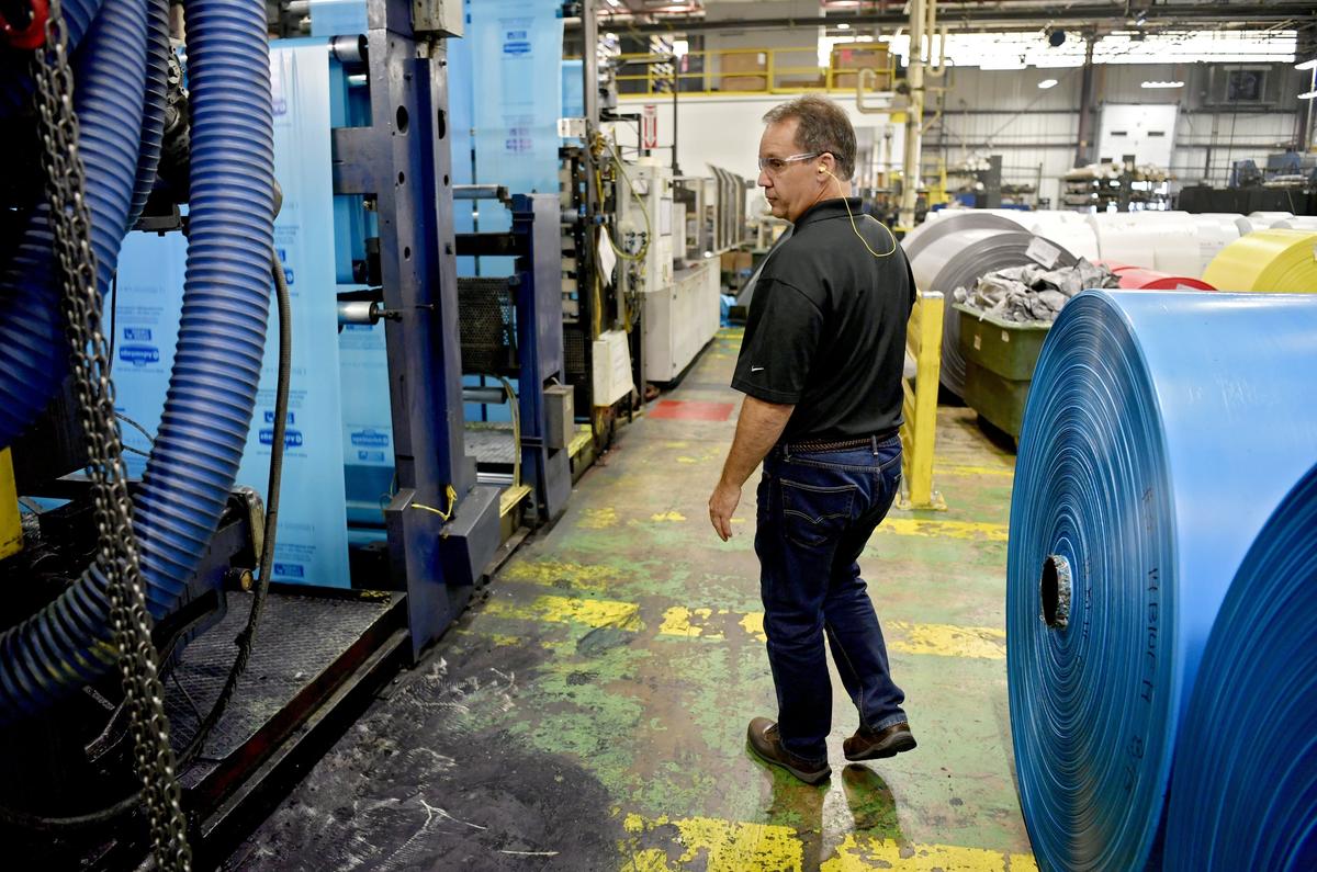 Hilex Poly plant manager Bill Zajac walks along a machine printing logos onto the plastic bags on Wednesday.