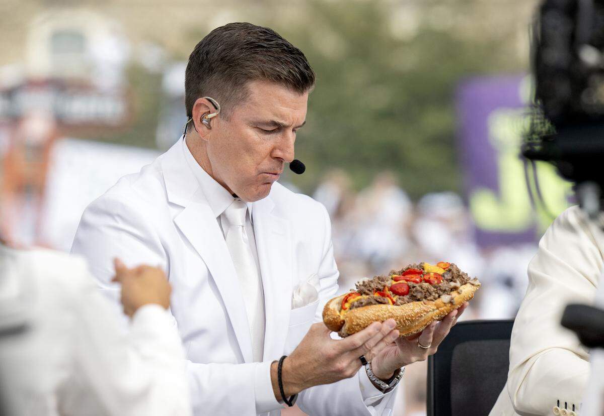 Rece Davis from ESPN’s College GameDay holds up a cheesesteak from Penn Steaks during the show on Saturday, Sept. 27, 2025.  