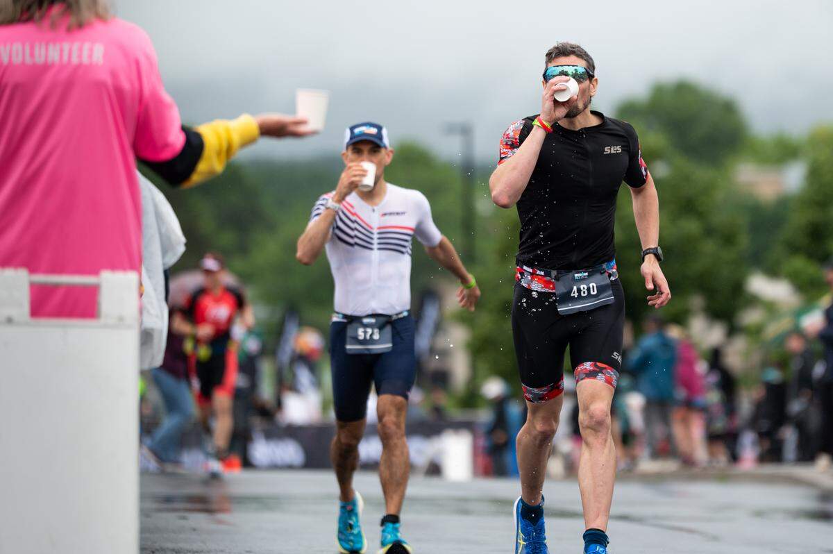 Athletes run and drink water from volunteers during the third leg of the Ironman 70.3 Happy Valley on Sunday, June 15, 2025 in State College, Pa.