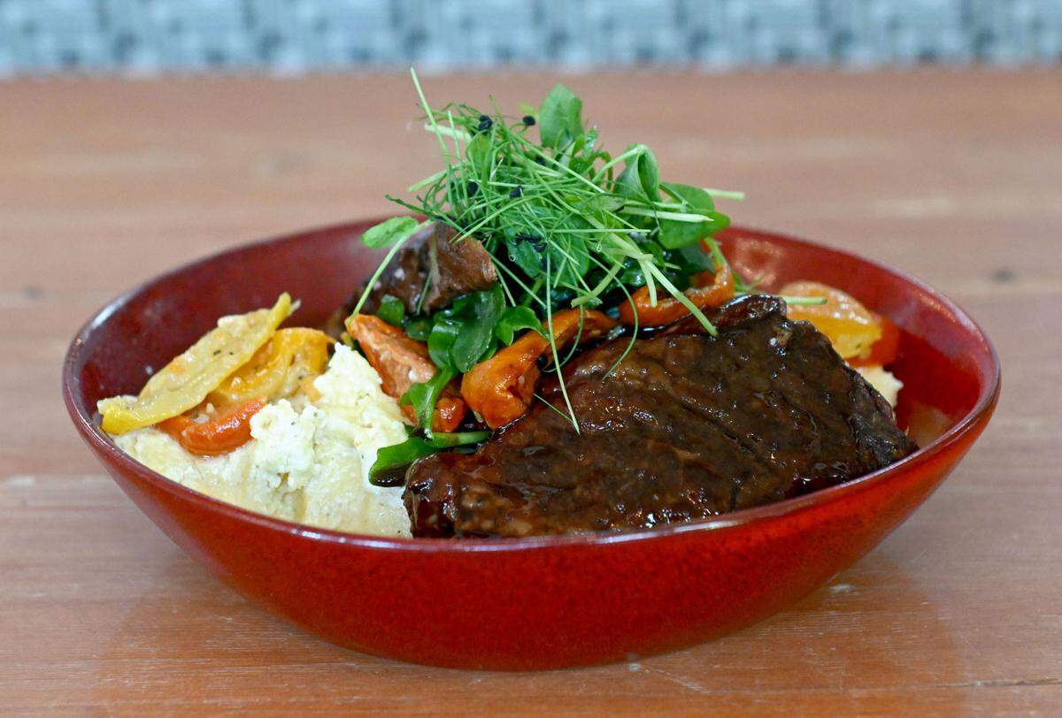 The southern IBC braised short rib at Gigi’s Southern Table. The dish features IBC root beer and sassafras infused short ribs served with Charleston grits and roasted tomatoes.