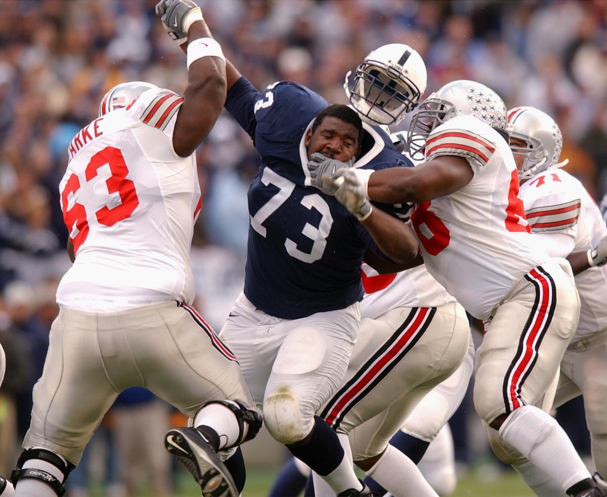 Penn State's Jimmy Kennedy (73) loses his helmet while beingdouble teamed  by Ohio State 's Adrien Clarke (63) and LeCharelsBentley, right, Staurday,  Oct. 27, 2001.