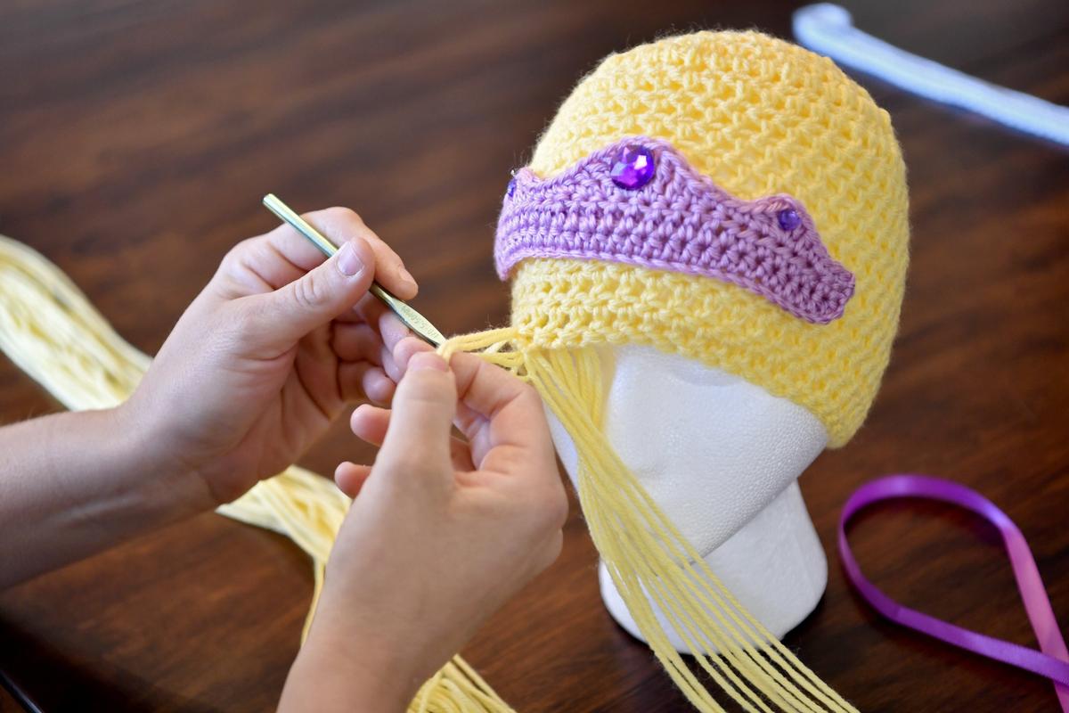 Karen Smitka works on adding hair to a beanie with a Rapunzel theme on June 3. The Brave Beanie Project makes beanies for children in the hospitals, from princesses and superheroes to animals and cartoon characters.