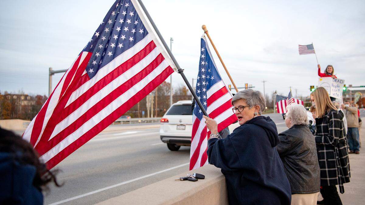 Kris Eng waves an American flag with fellow Trump supporters on the Waddle Road interchange on Thursday, Nov. 5, 2020.  