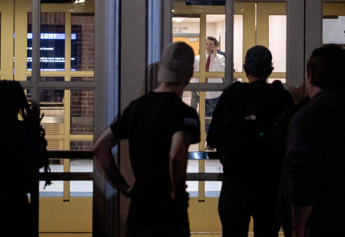 Protesters watch Alex Stein as he walks in a hallway of the Thomas Building after the “Stand Back & Stand By” event was canceled on Monday, Oct. 24, 2022.