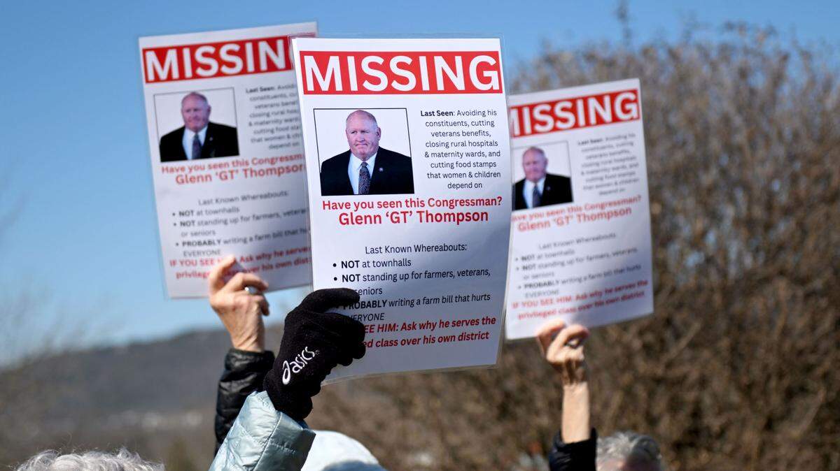 People hold up signs of U.S. Rep. Glenn Thompson that say “missing” during a protest outside his Bellefonte office.