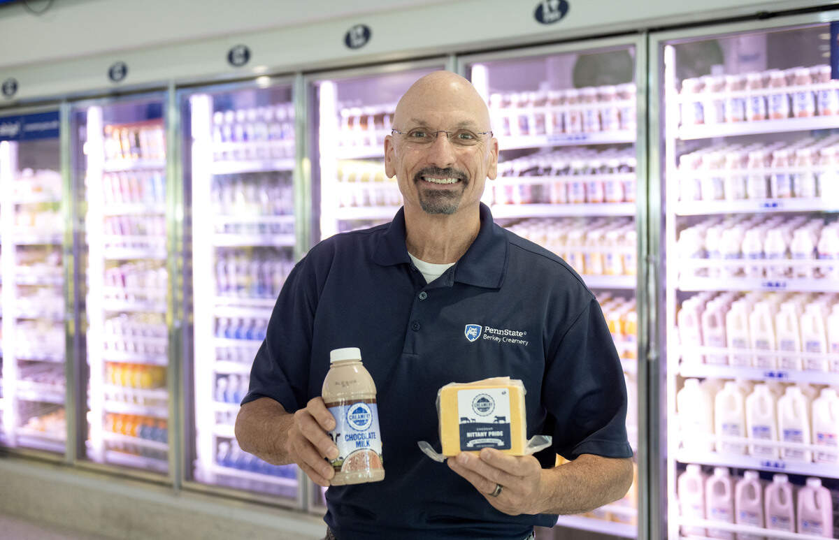 Jim Brown, manager of sales and marketing for the Penn State Berkey Creamery, holds a bottle of chocolate milk and cheddar cheese in the store on Thursday, June 4, 2026.