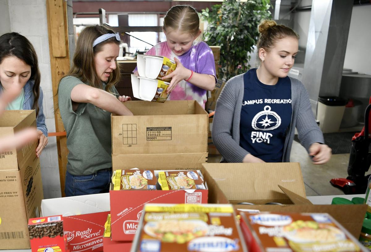 Ellie Jones, 8, and volunteers from The Navigators Penn State help to pack boxes for Common Food on April 18.