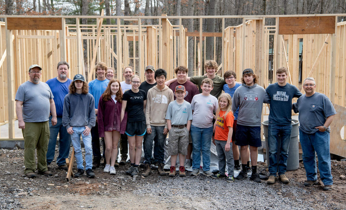 Scouts from Troop 32 stand in front of the David O’Connell Health Education Building at Seven Mountains Scout Camp on March 19 as they volunteered hours to prep the wood for the building.