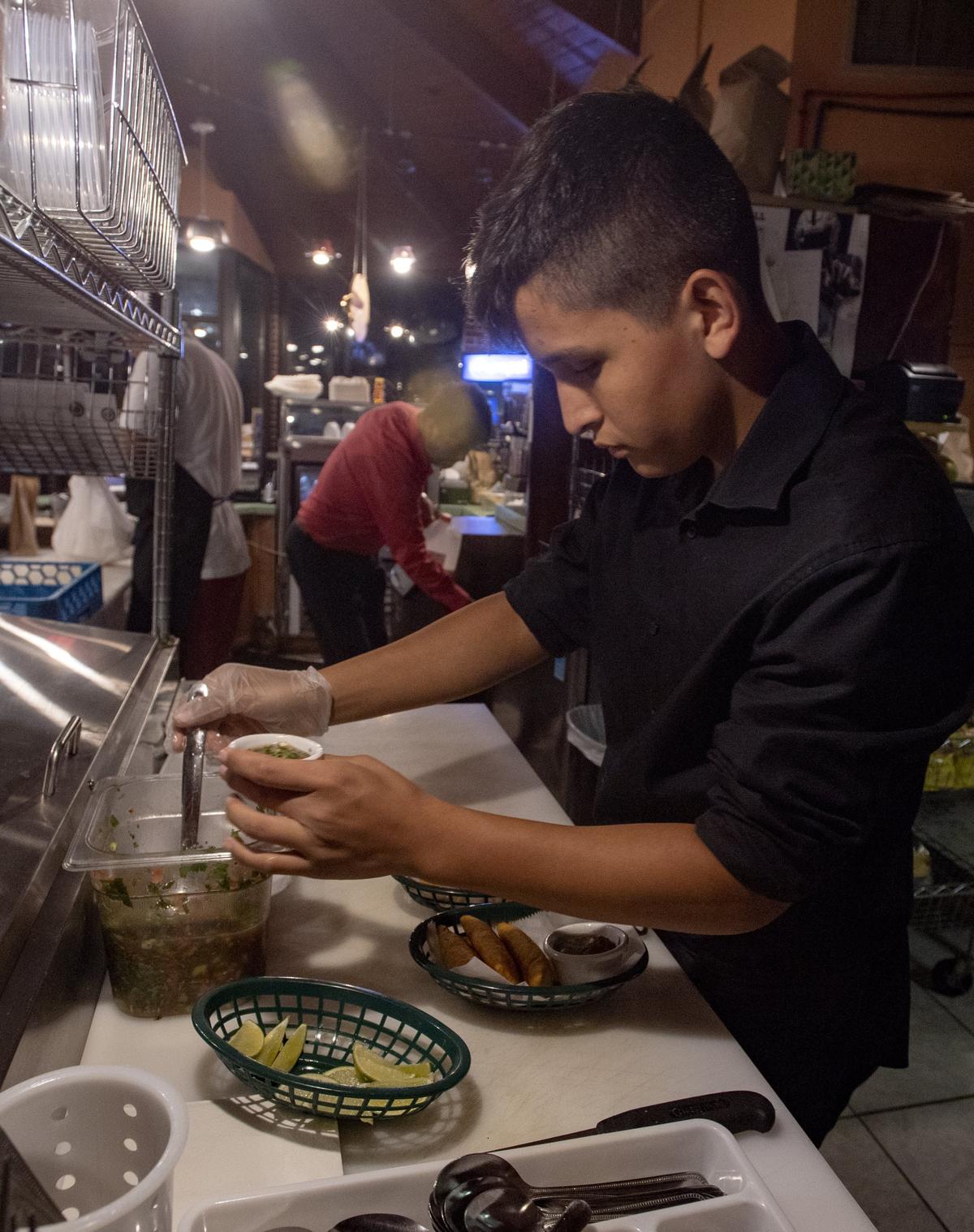 George Rusinque scoops spicy pico de Gallo to go with an order of empanadas at El Gloton on Friday, Oct 19, 2018.
