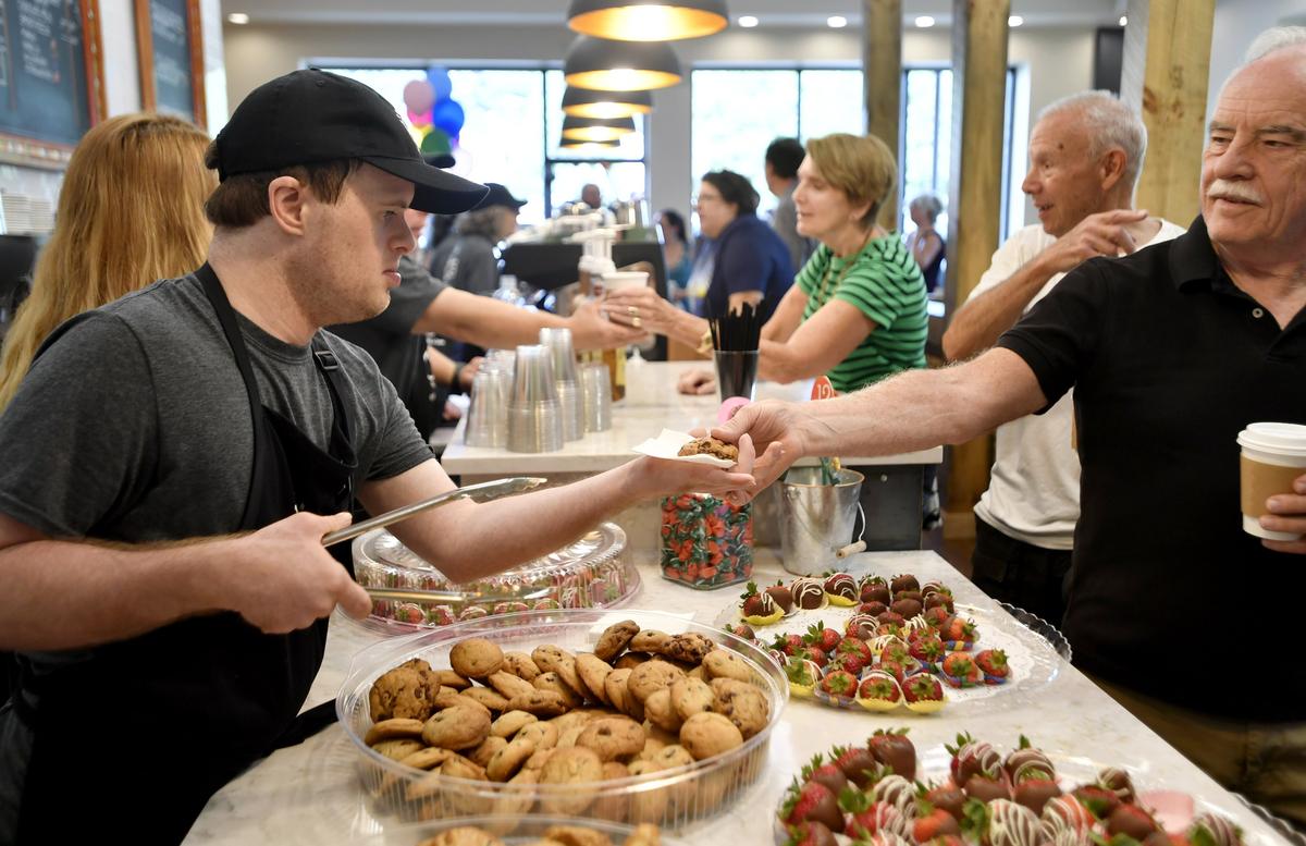 Gareth Roof hands a cookie to a customer at Good Day Cafe for the ribbon-cutting celebration on Aug. 17. Good Day Cafe employs community members with intellectual disabilities.