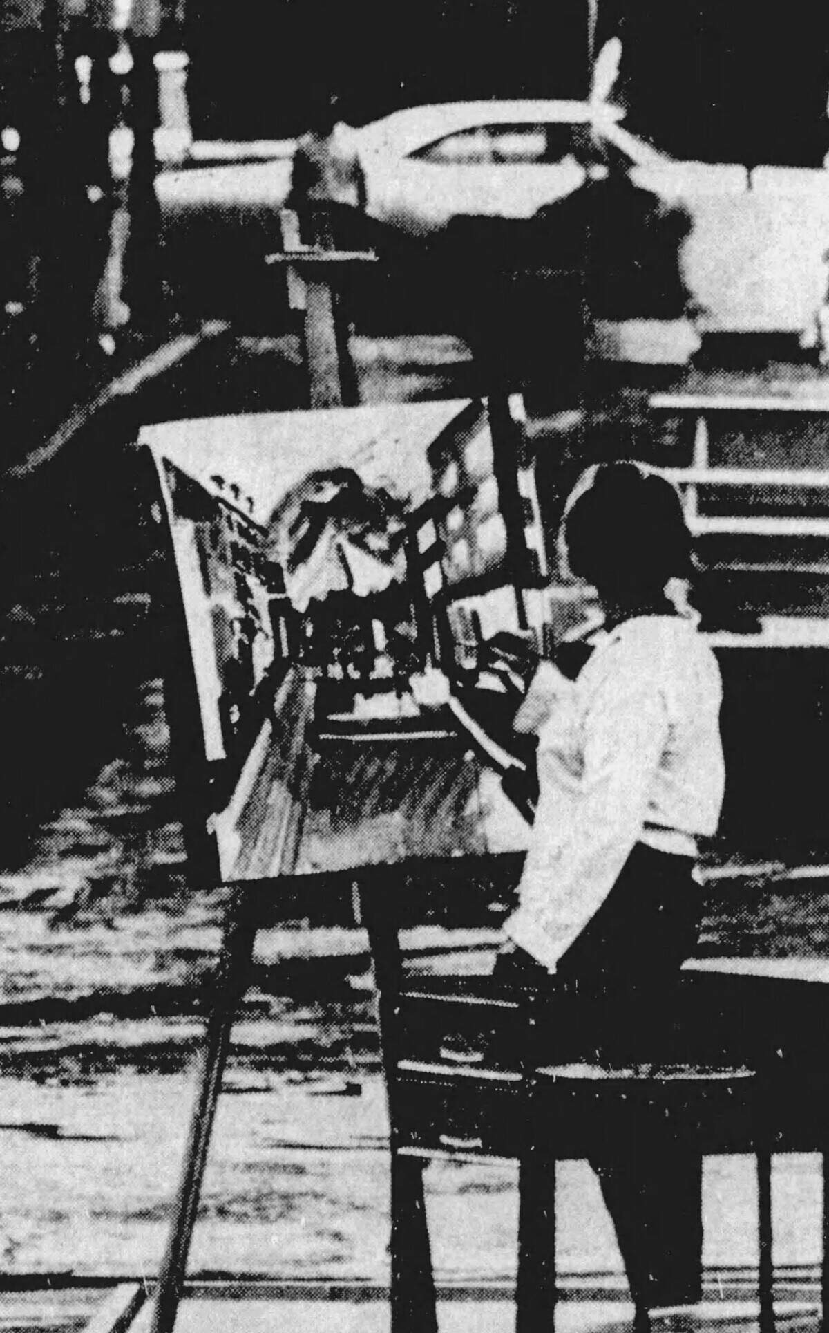 An unnamed artist braves the rain on South Allen Street during a wet week at the first-ever Central Pennsylvania Festival of the Arts in July 1967.