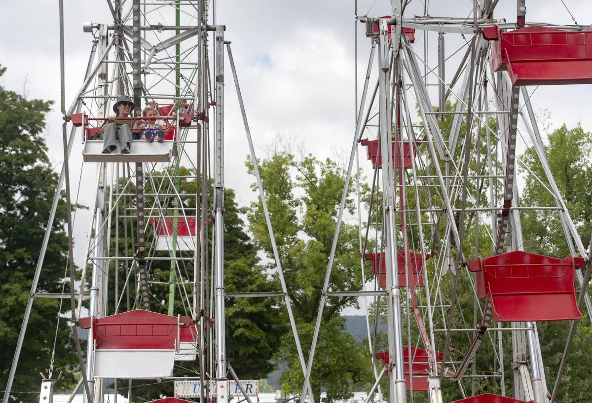 Fairgoers enjoy a ride on the Ferris wheel, next to the silent Ferris wheel to honor Jack Garbrick on Wednesday at the Centre County Grange Fair.