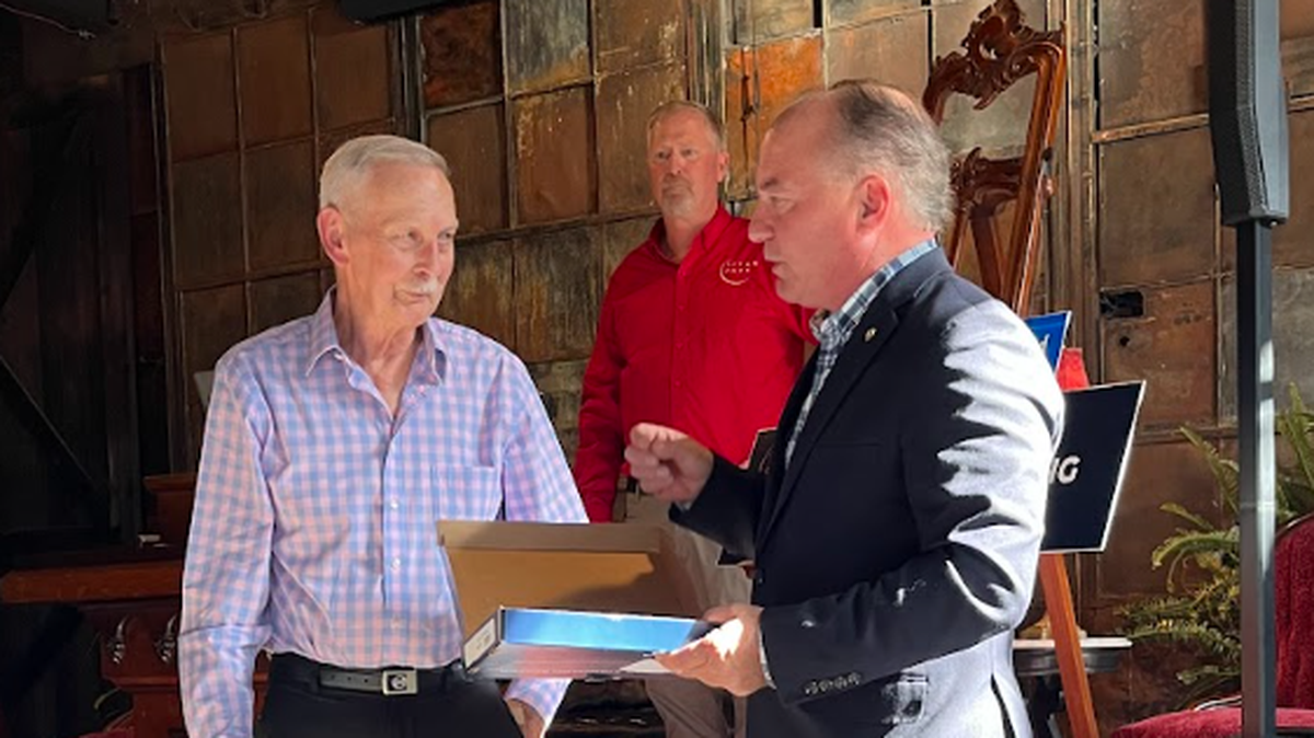 State Representative Kerry Benninghoff, R-Bellefonte, presents Gary Dunklebarger with a Pennsylvania state flag as thanks for his 57 years of service to the Titan Energy Park as an electrician. Titan Park owner Joe Leahey stands in the background.