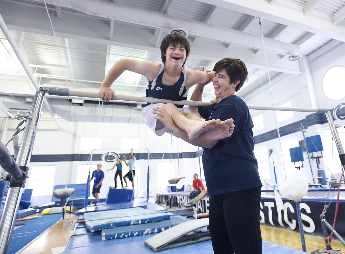 Centre County resident Nathan Jewell, 12, and Centre County Special Olympics Coach Courtney Simpson smiles as Nathan does the high bar during the Special Olympics Friday, June 1, 2018 at the White Building at Penn State.