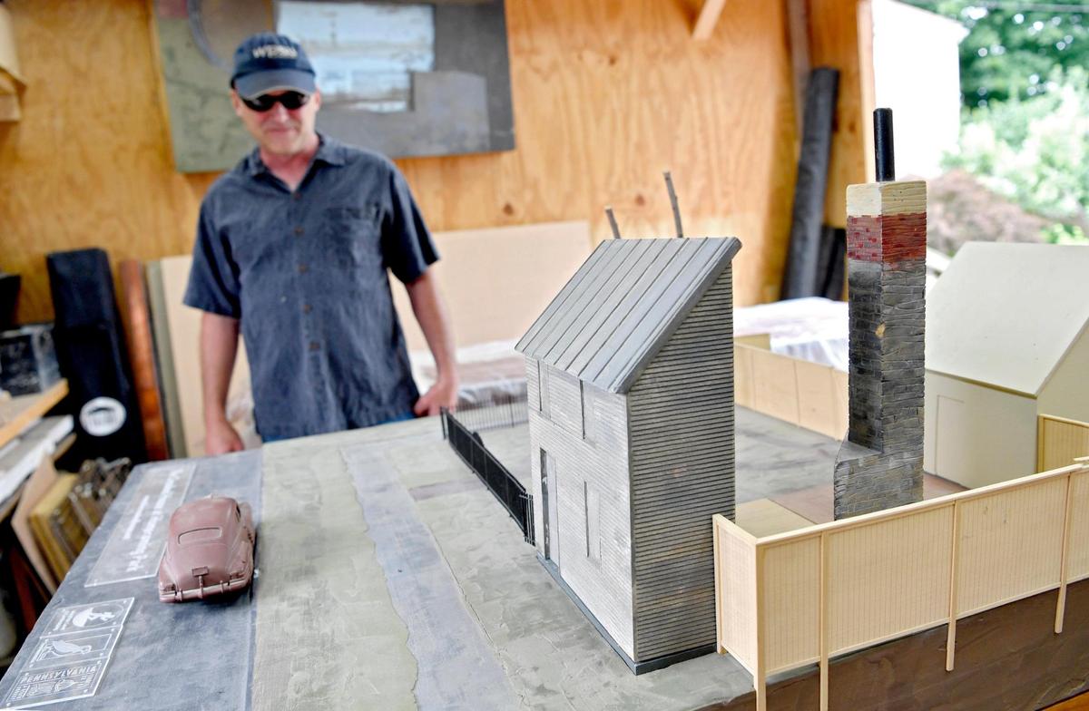 Artist and architect Benjamin Fehl shows a diagram of what The Crooked House art piece will be when it is completed with a facade of the front of the house and the old fireplace.