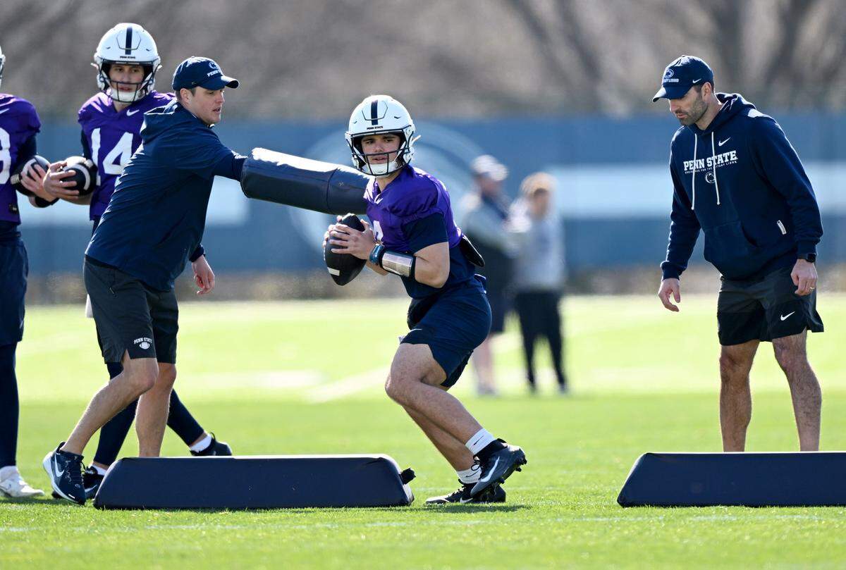 Penn State quarterback Rocco Becht runs a drill as quarterbacks coach Jake Waters watches during practice on Thursday, April 9, 2026.  
