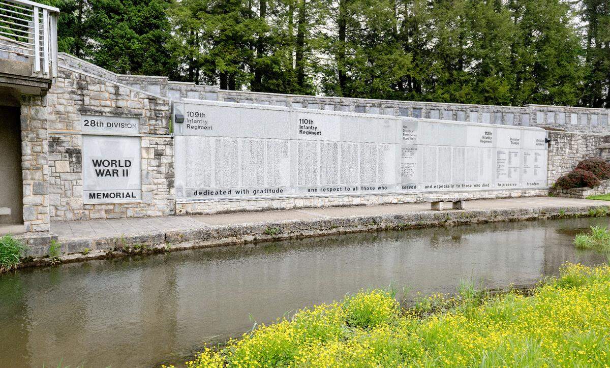 A stream flows by the World War II memory wall that is part of The 28th Infantry Division shrine at the Pennsylvania Military Museum. The wall commemorates the 28th Div. soldiers who were killed or died of injury received from combat in WWII.