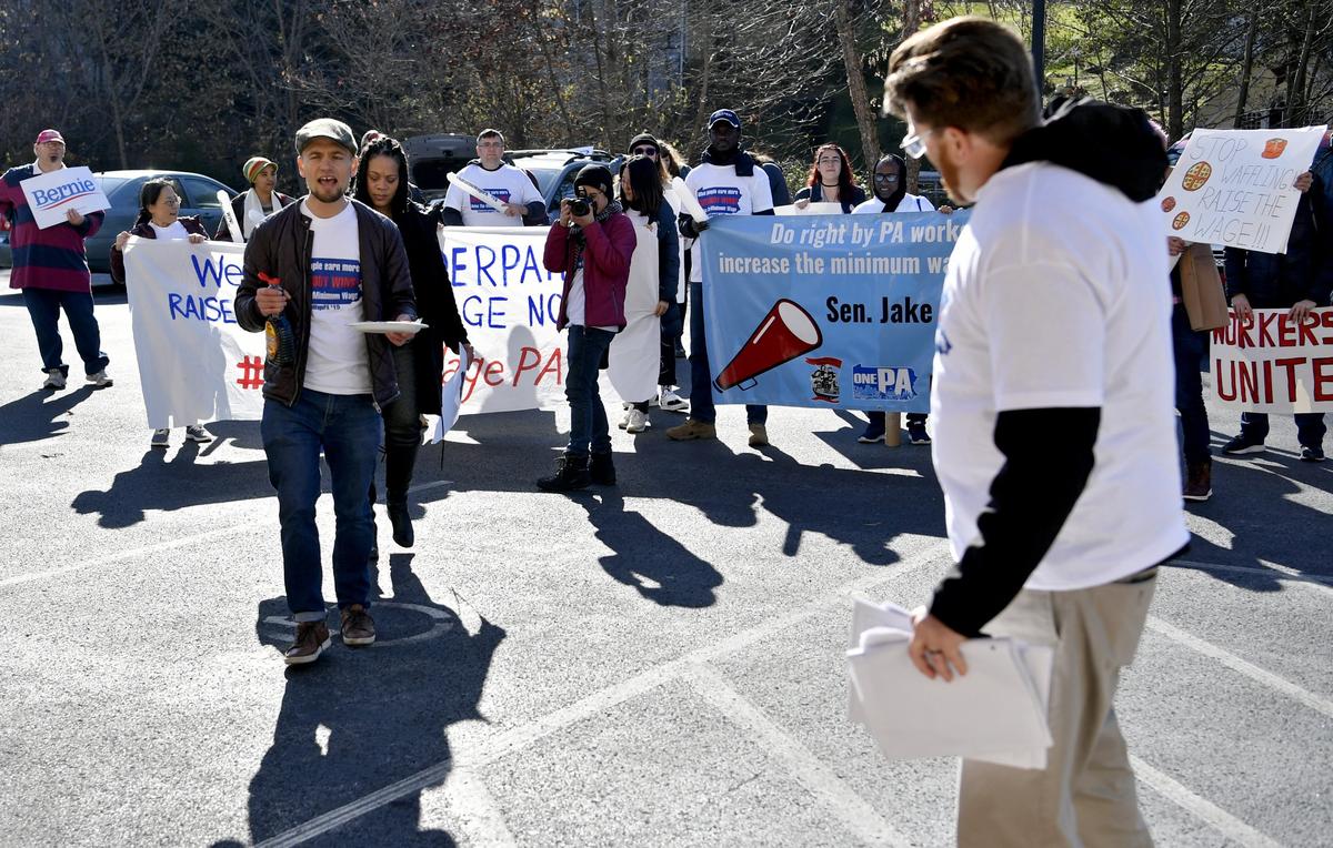 Manuel Rosaldo and members of the Centre County Wage Justice Coalition chant as they deliver waffles and petitions to state Sen. Jake Corman’s office on Nov. 15.
