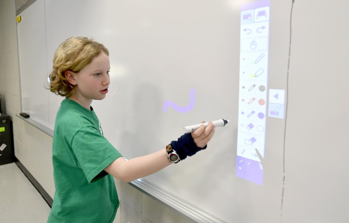 Fifth grader Zoe Salter shows how the new projection systems work at Corl Street Elementary on Friday, Jan. 11, 2018. Each classroom will have one of the systems when the construction is completed.