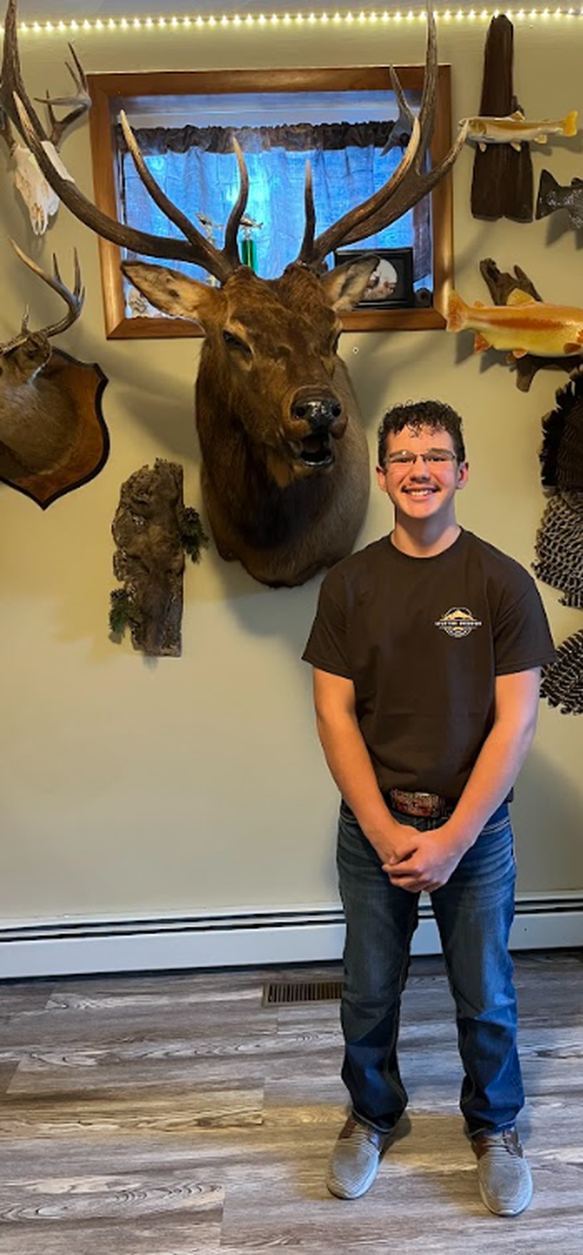 CJ Coudrient, Founder of Uplifting Outdoors, sands next to the Rocky Mountain bull elk he harvested on a gifted hunt during his ERMS treatment.