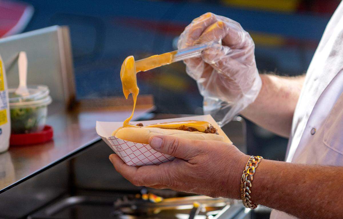 Bob Vogely of Dog’s on the Run makes a chili cheese dog for a customer on Thursday, Aug. 31, 2023.
