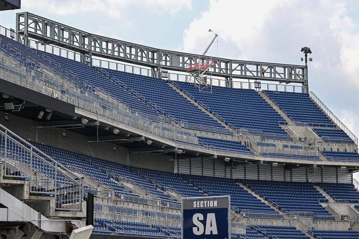 Workers walk along the super ribbon board structure in the south end zone. The new super ribbon boards will be unveiled during the 2024 home season.