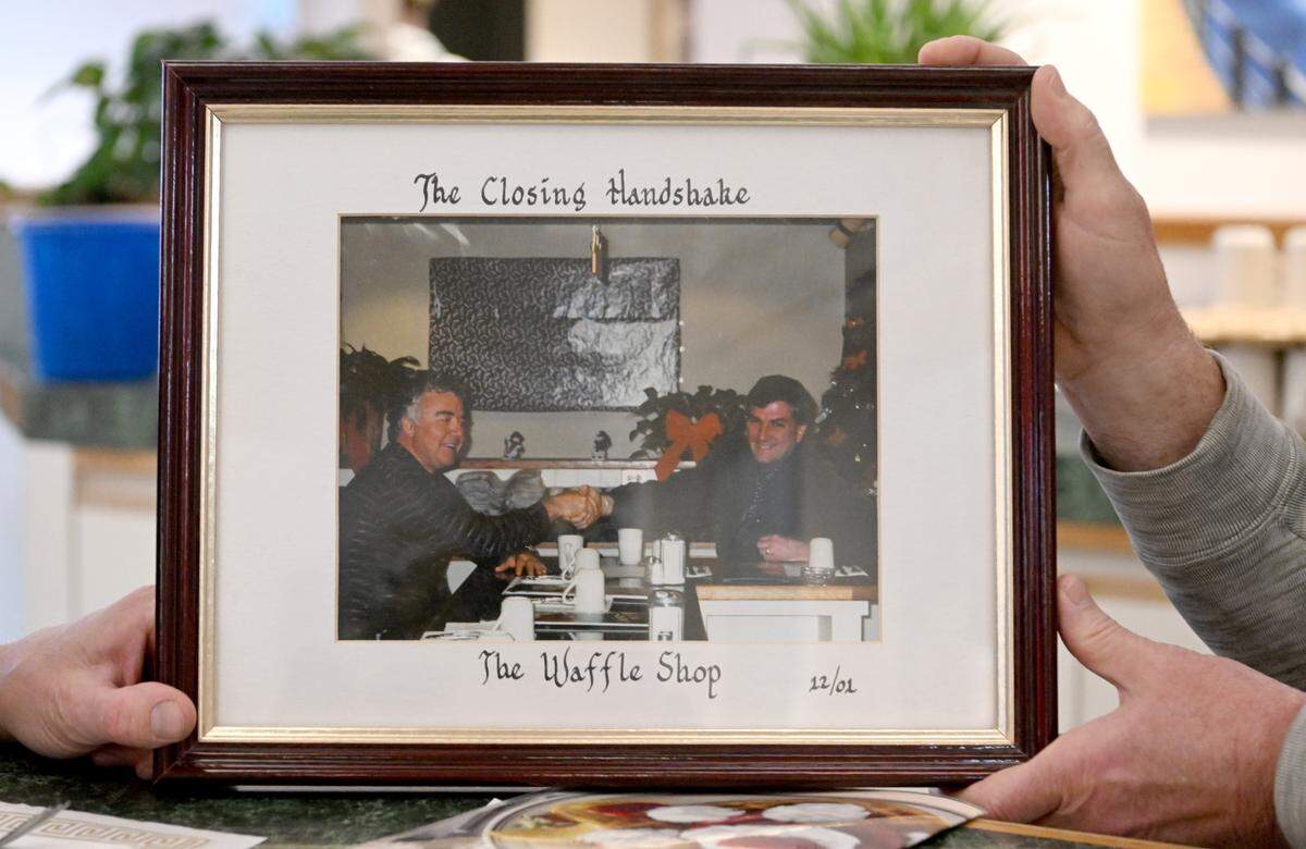 An old photo of John Dimakopoulos and Greg Kight shaking hands when Kight bought the Bellefonte and downtown Waffle Shop locations.