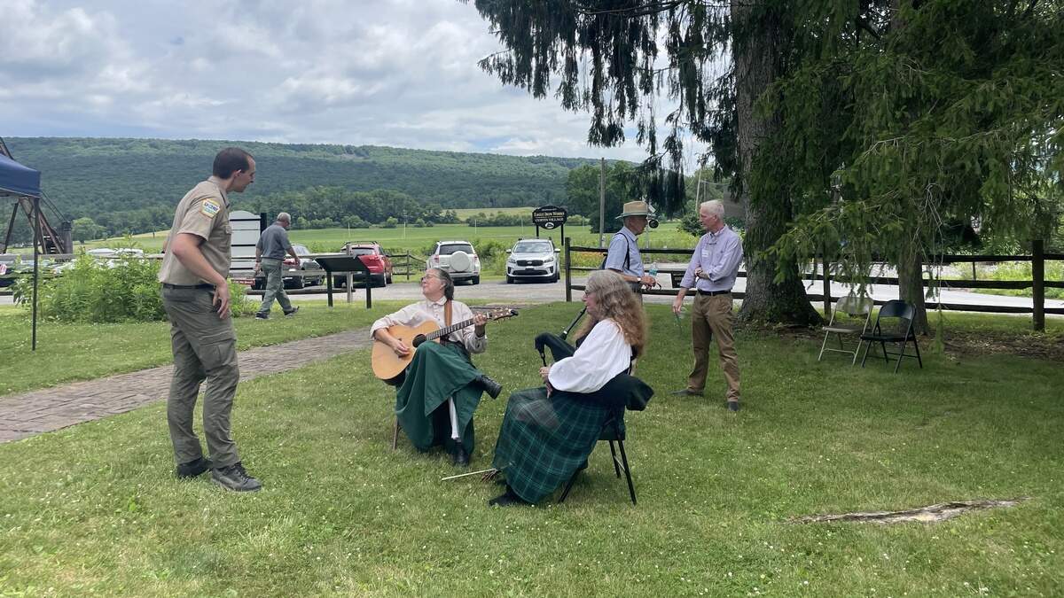 Musicians playing Irish music chat with a DCNR officer on the Curtin mansion lawn.