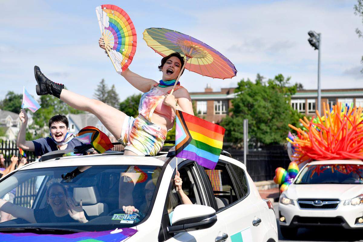 Mary Rose Valentine cheers out of the sunroof of a car with her rainbow fan and umbrella in the State College Pride Ride organized by the Centre LGBTQA Support Network on June 12.