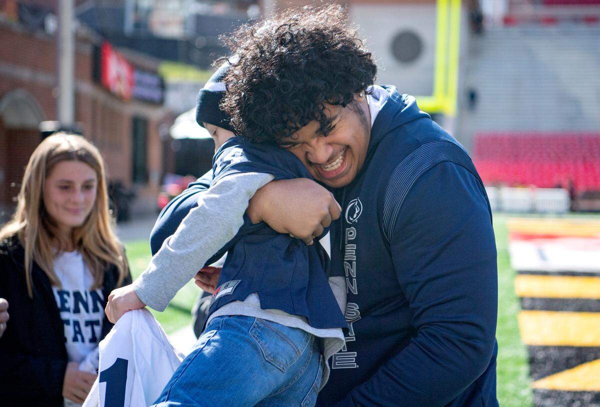 Penn State defensive tackle Dvon Ellies picks up Sawyer Bell, 9, for a hug, as he greets him and his family at Maryland Stadium on Saturday, Nov. 6, 2021. Sawyer is part of team IMPACT.
