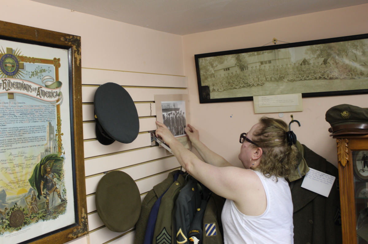 The book’s co-editor and Clarence resident Kelly Miller fixes a sign in the David House Heritage Museum’s military corner.