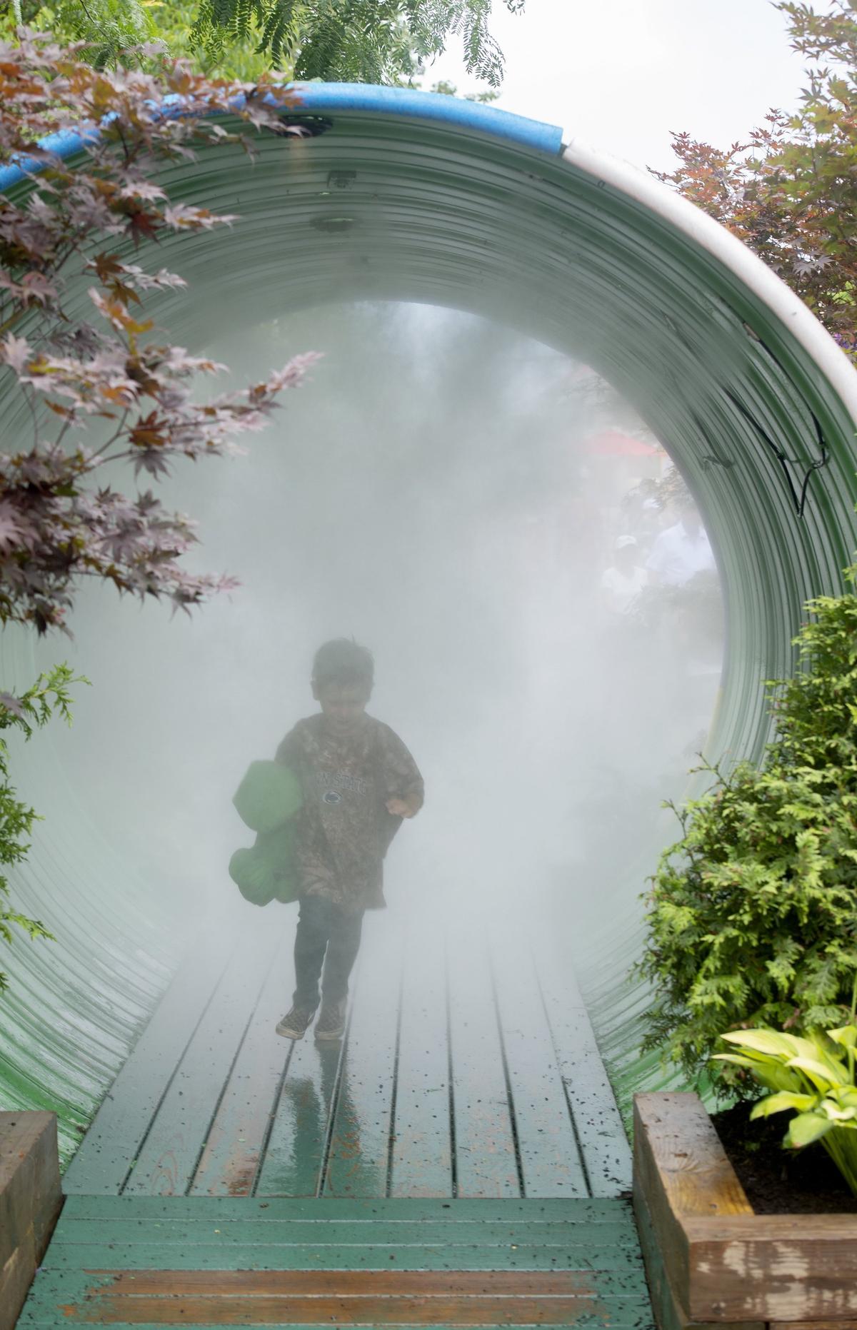 A youngster runs through the mister on Allen Street at the Central Pennsylvania Festival of the Arts on Thursday, July 11, 2019.